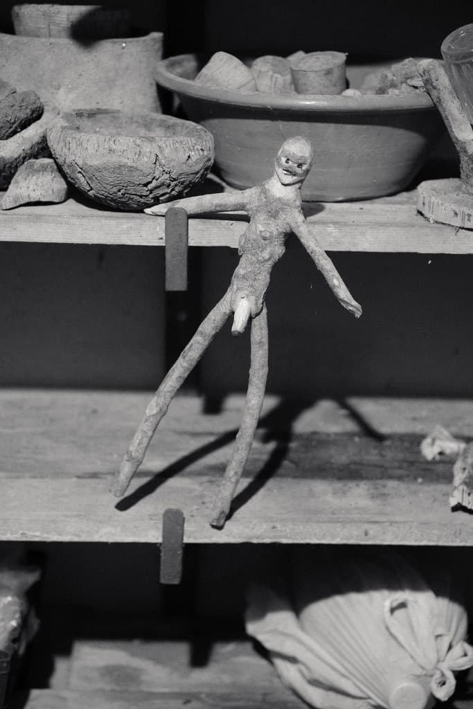 A clay figure hanging from a workshop shelf.