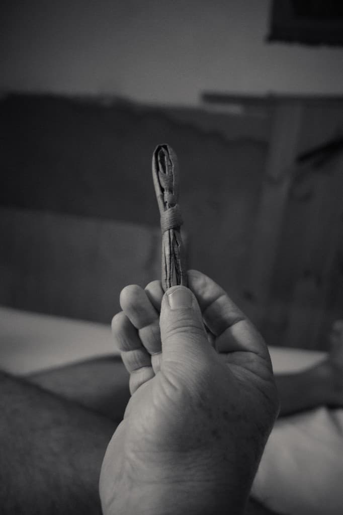 A hand holding a small bundle of wrapped leaves.